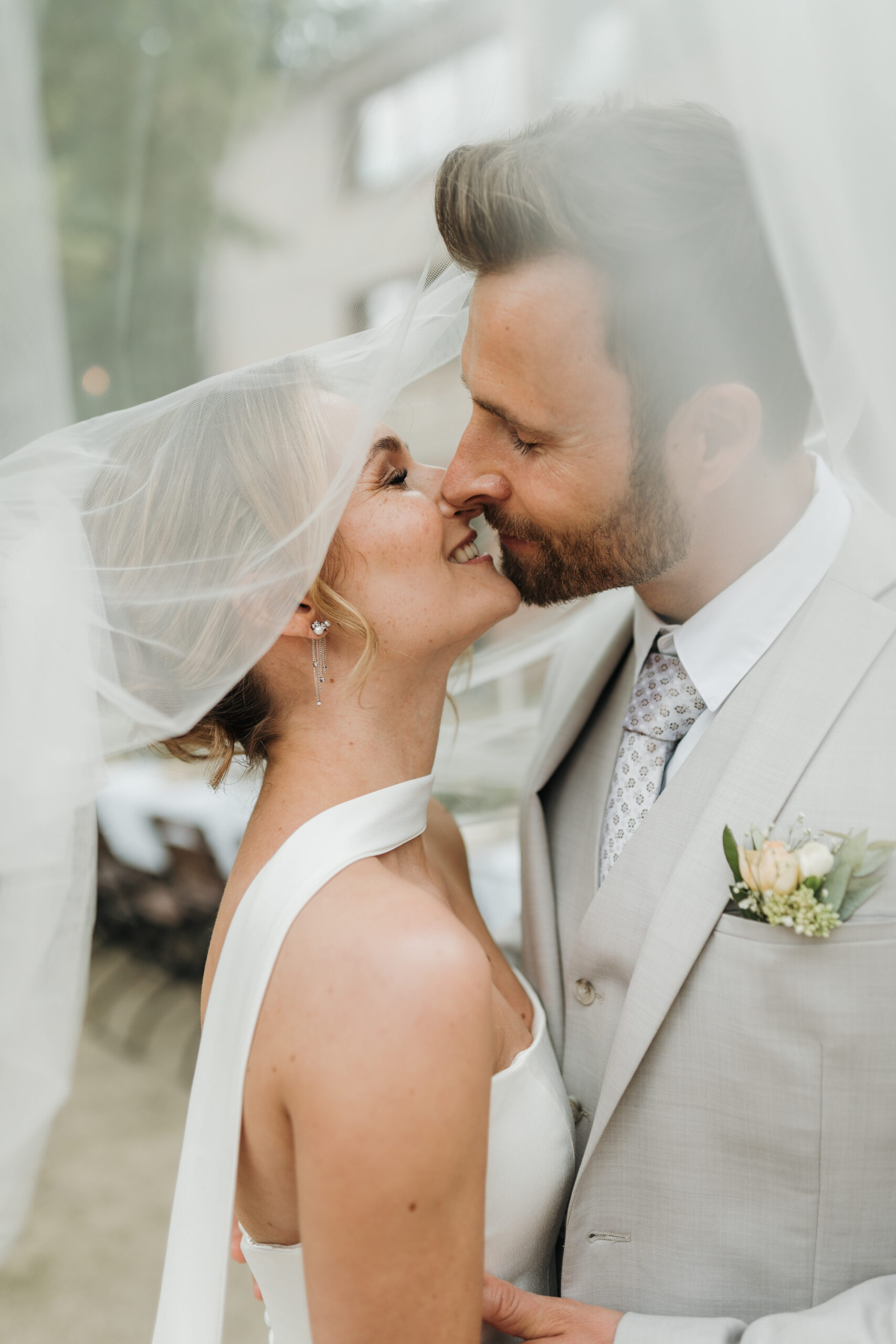 Brautpaar küsst sich unter einem Schleier.